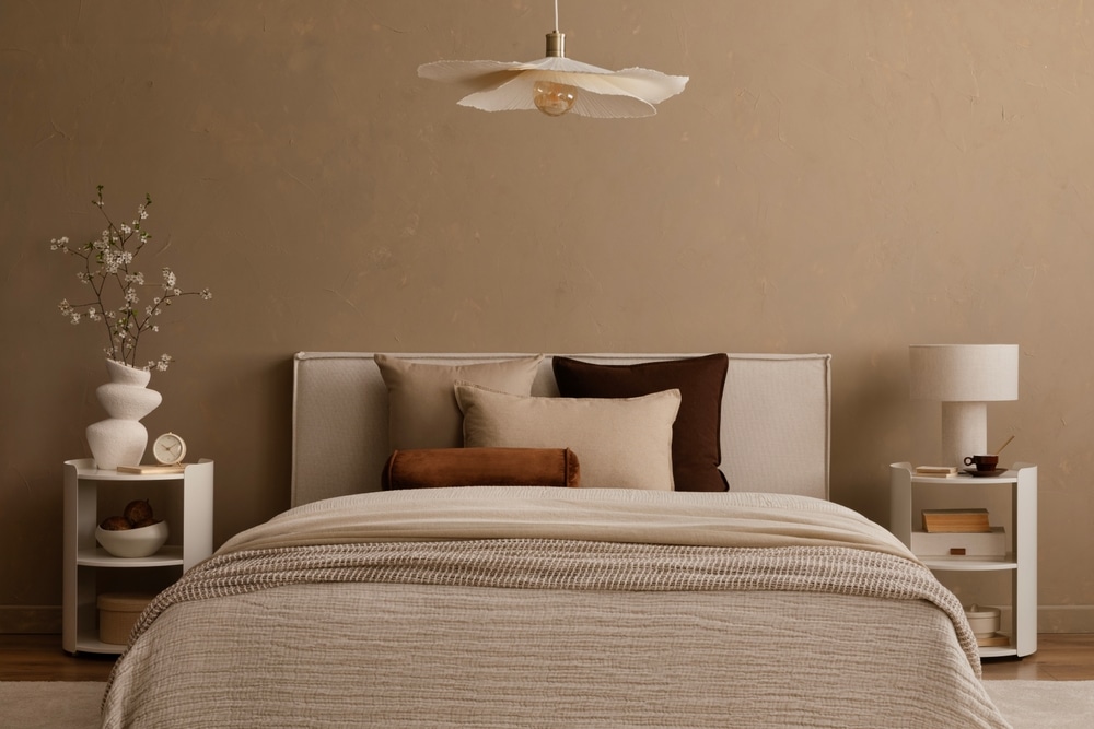 Décoration Chambre Minimaliste et Bohème aux Tons Terreux Chambre minimaliste aux tons terreux avec lit beige, coussins décoratifs et luminaire suspendu pétale design.