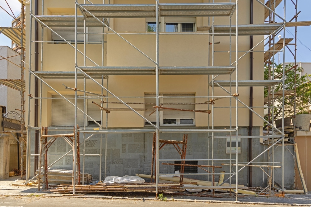 Échafaudage métallique sur la façade d'un immeuble beige en cours de rénovation.